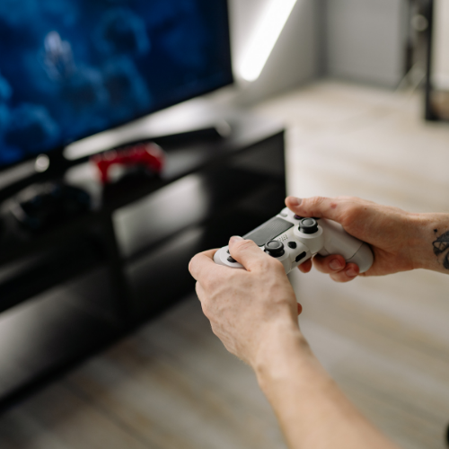 Hands holding a game controller in front of a television representing video game music composition